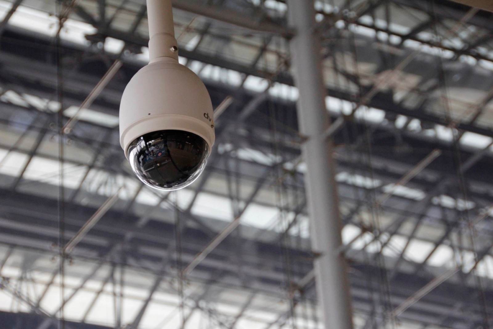 A dome security camera hanging under a steel roof