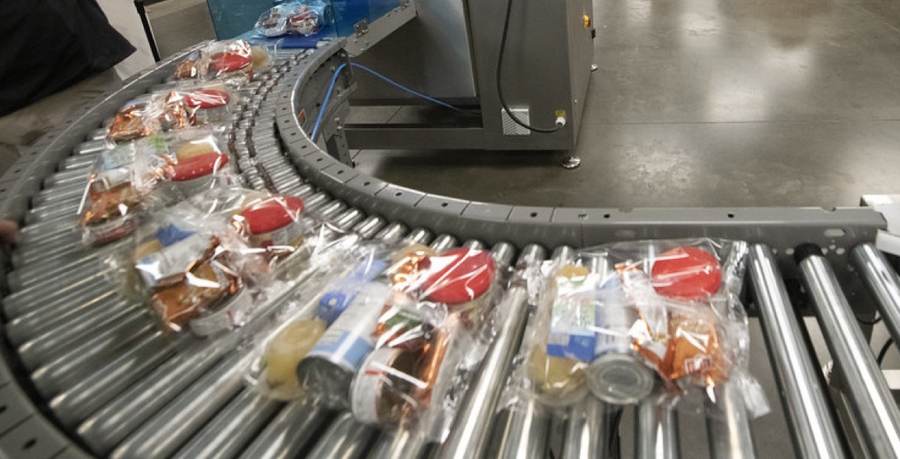 Packed food items moving along a roller conveyor on a packing line